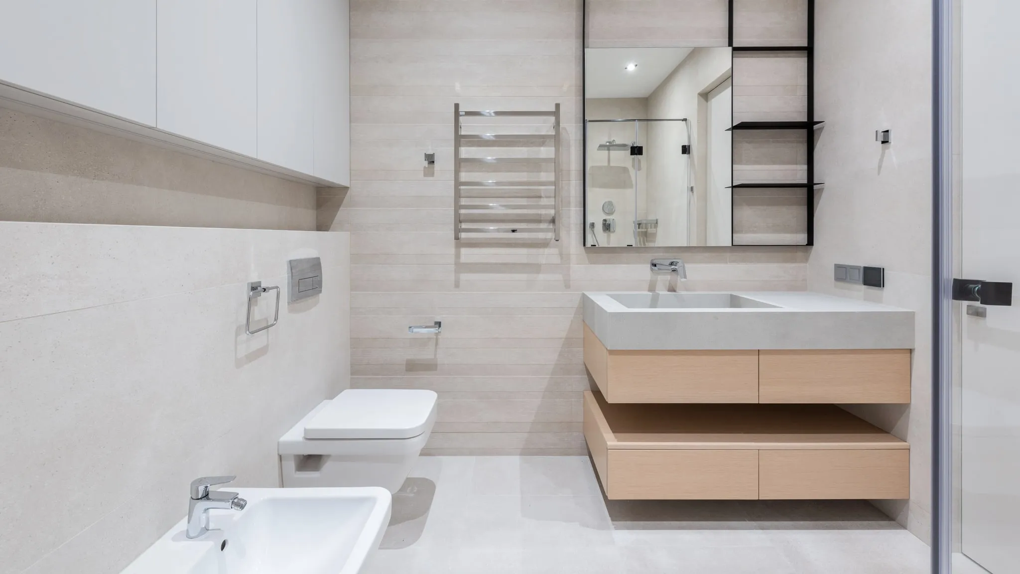 Een lichte, minimale badkamer met houten meubel en een spiegel.
